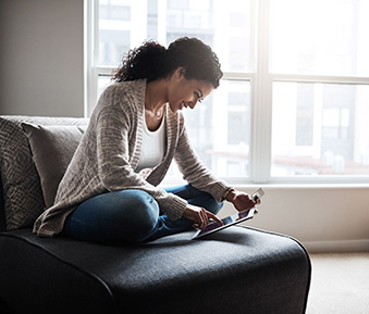 Woman comfortably reviewing VitalChek FAQ on mobile device